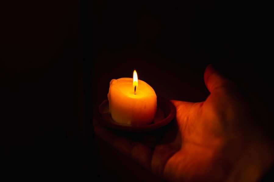 burning-candle-mans-hand-dark-backgrounda-man-prayer