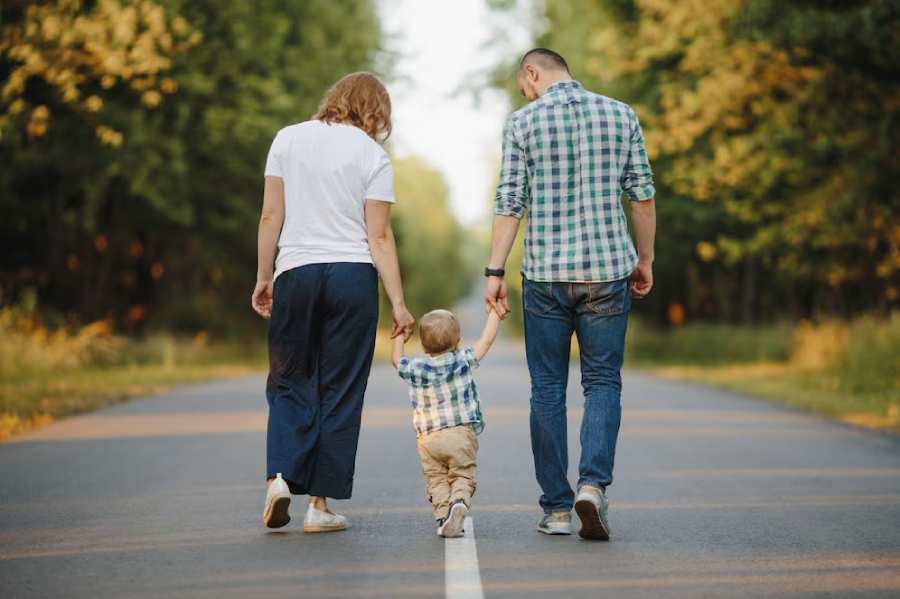 parents-holding-their-little-son-are-walking-road